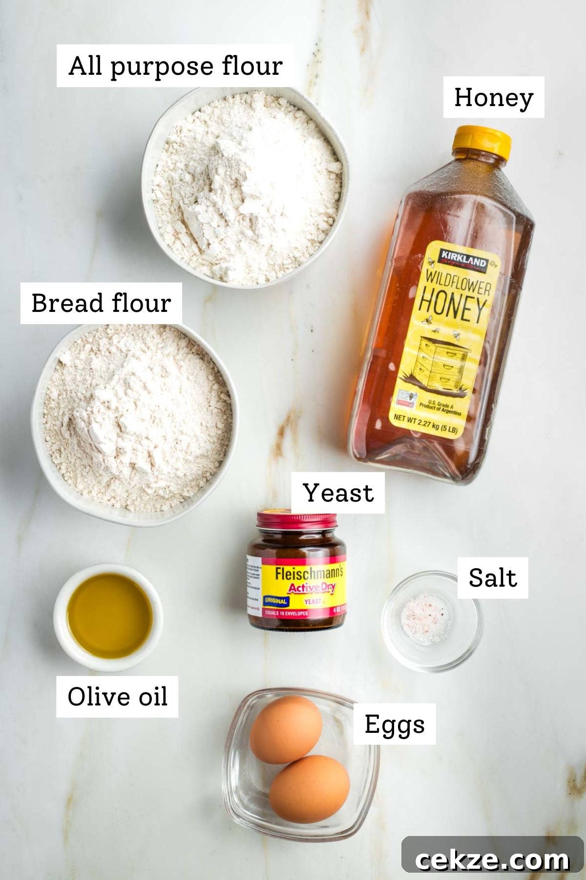 Sweet Round Challah Recipe: Soft, Shiny Braided Dinner Bread 3 Labeled ingredients for challah: flour, honey, yeast, olive oil, salt and eggs.