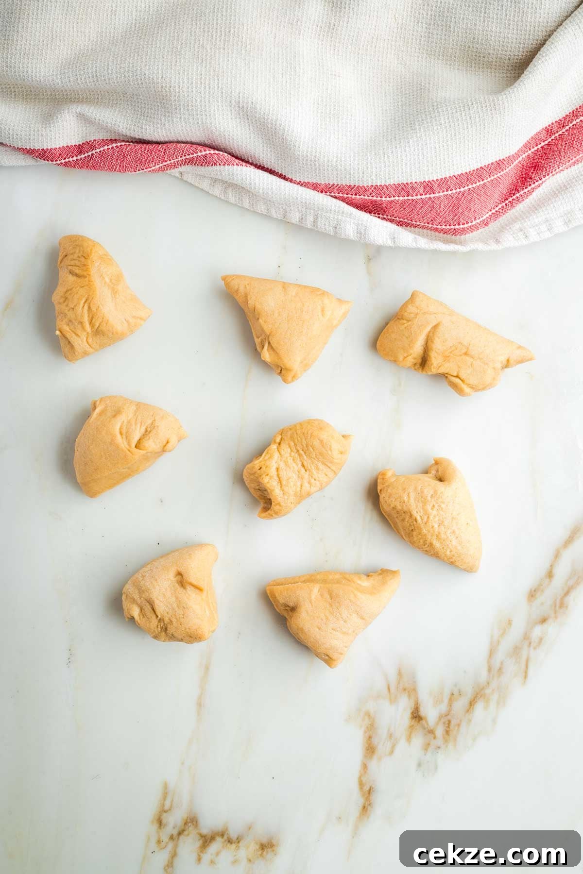 Sweet Round Challah Recipe: Soft, Shiny Braided Dinner Bread 20 8 small pieces of dough and a kitchen towel, covering more dough pieces.