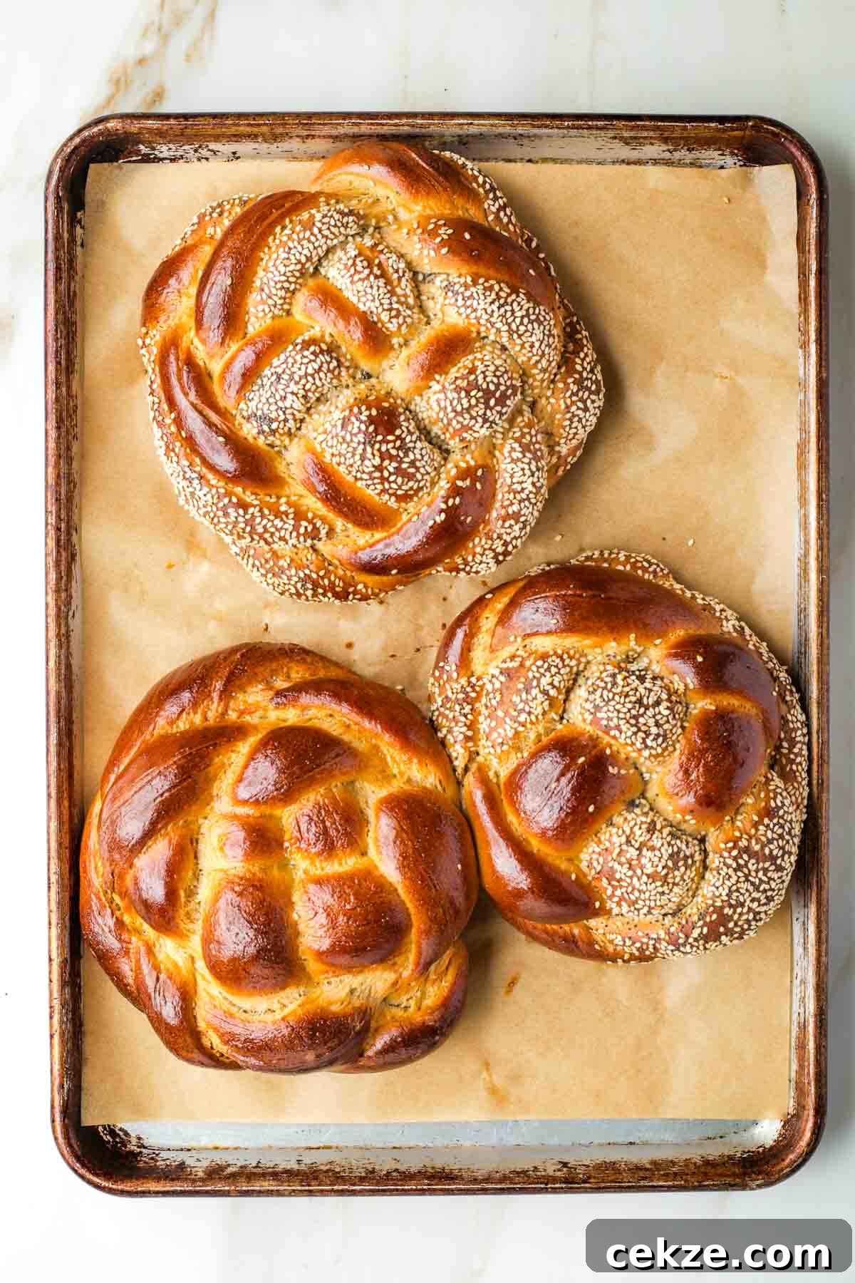 Sweet Round Challah Recipe: Soft, Shiny Braided Dinner Bread 34 Golden brown, round loaves of braided challah bread.