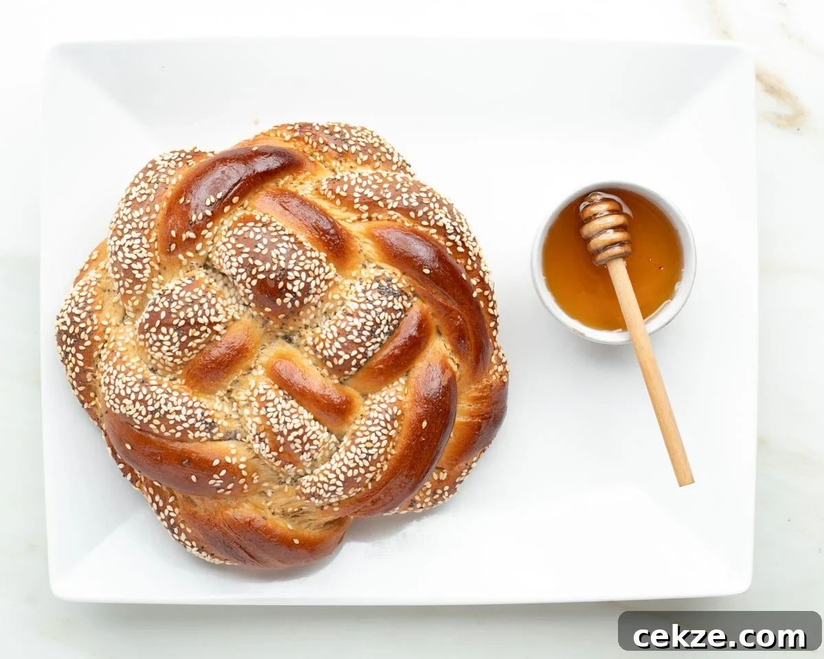 Sweet Round Challah Recipe: Soft, Shiny Braided Dinner Bread 37 Round, braided challah bread with sesame seeds and a side dish of honey.