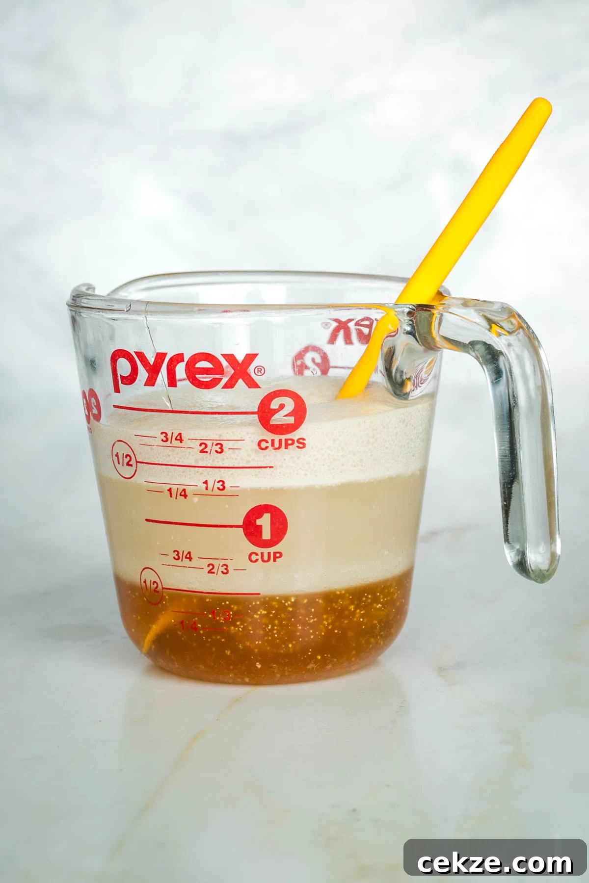 Sweet Round Challah Recipe: Soft, Shiny Braided Dinner Bread 6 Side view of yeast, honey and water proofing in a glass measuring cup.