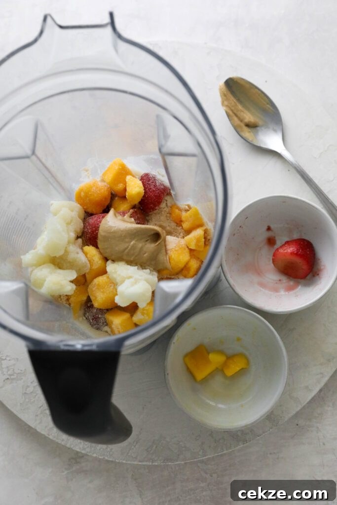 Strawberry Mango Smoothie Bowl Recipe for Creamy Tropical Breakfast 4 frozen mango, cauliflower, and strawberries in blender with cashew butter