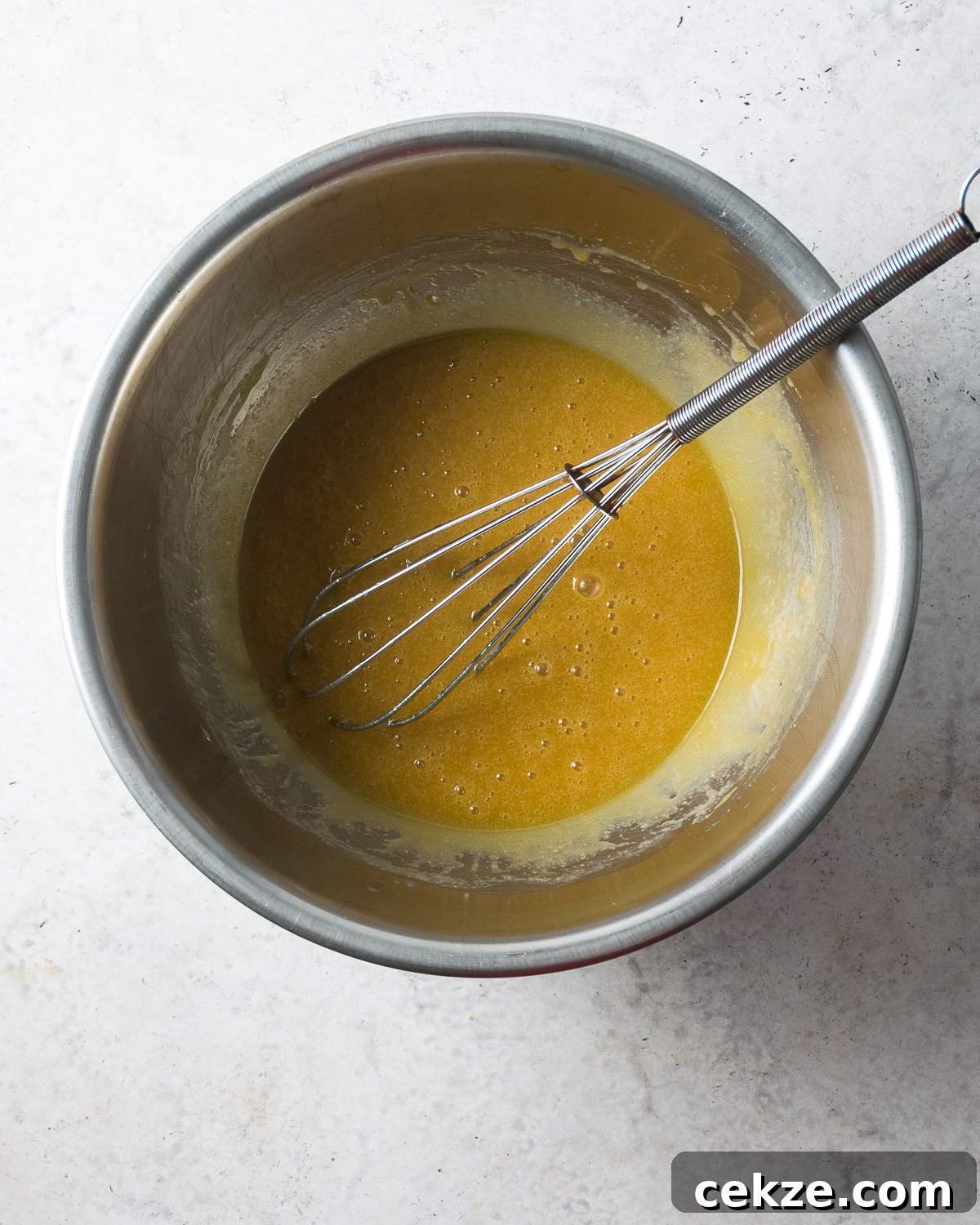 Melted butter and sugar whisked in a metal bowl.
