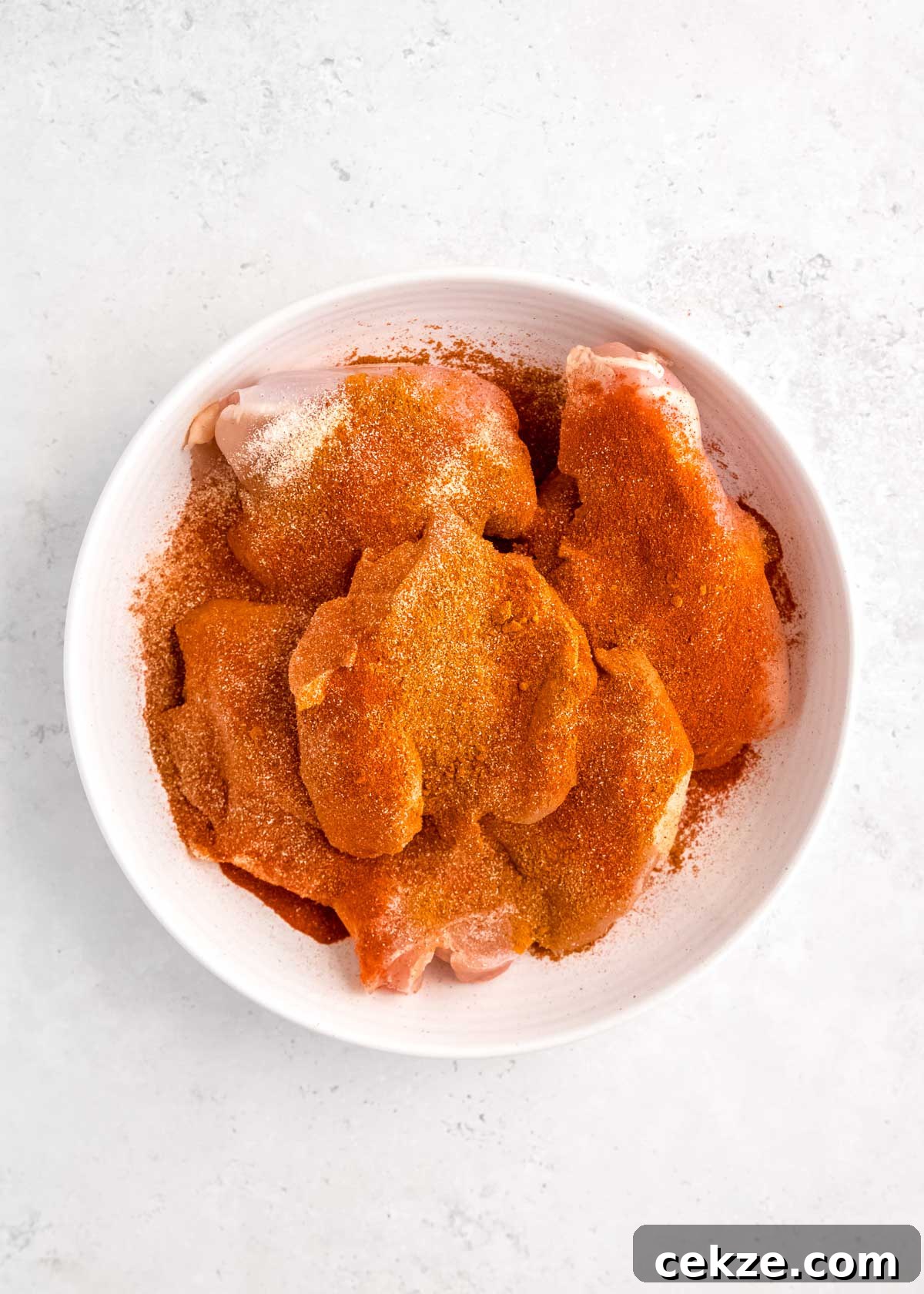 raw, seasoned chicken in white bowl