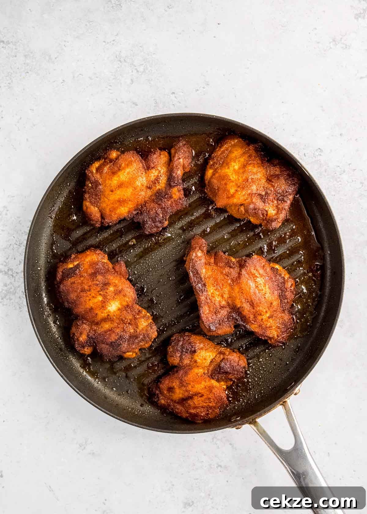 overhead image of chicken being cooked on grill pan