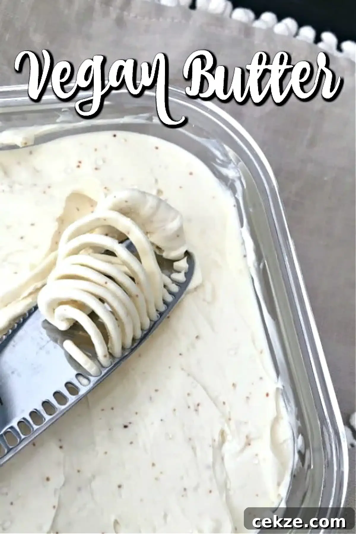 dairy free butter in a square glass container, a butter knife spreading a dollop of butter across the surface.