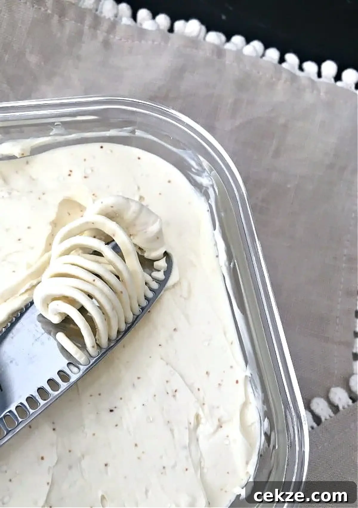 dairy free butter in a square glass container, a butter knife spreading a dollop of butter across the surface.