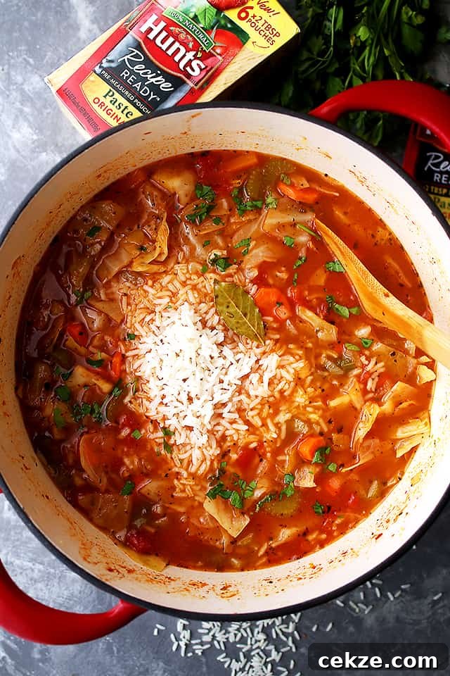 This quick and easy cabbage soup is made with a flavorful tomato broth loaded with tender rice and lots of veggies. Stirring cooked rice into cabbage soup.