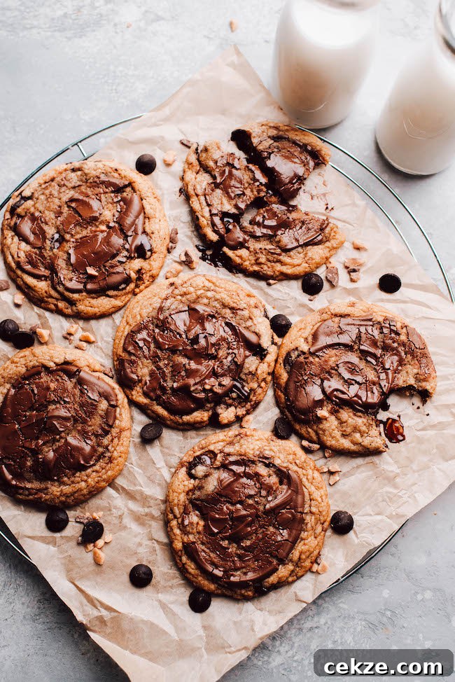 Nutella Toffee and Chocolate Chip Cookies 3 Nutella Toffee chocolate chip cookies on a parchment lined cooling rack with glasses of milk