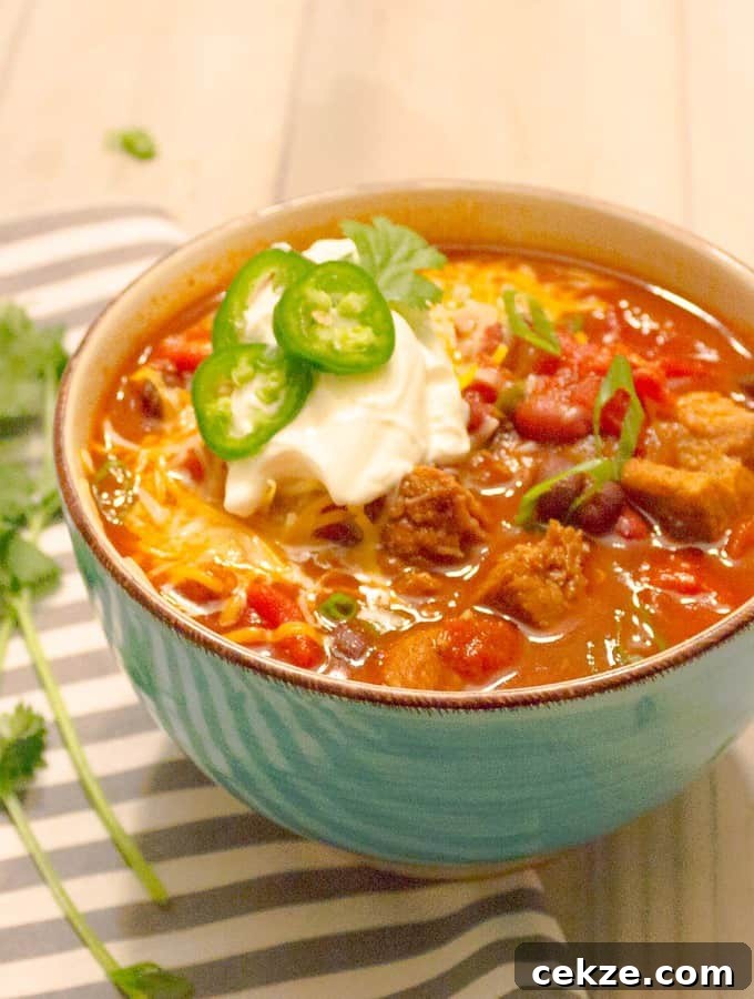 Instant Pot Red Pork Carnitas Chili Recipe 2 Instant Pot Pressure Cooker Red Pork Chili in a bowl with ganishings in a blue bowl on a gray striped napkin.