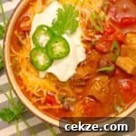 Instant Pot Red Pork Carnitas Chili Recipe 8 Instant Pot Pressure Cooker Red Pork Chili in a bowl with ganishings on a gray striped napkin.