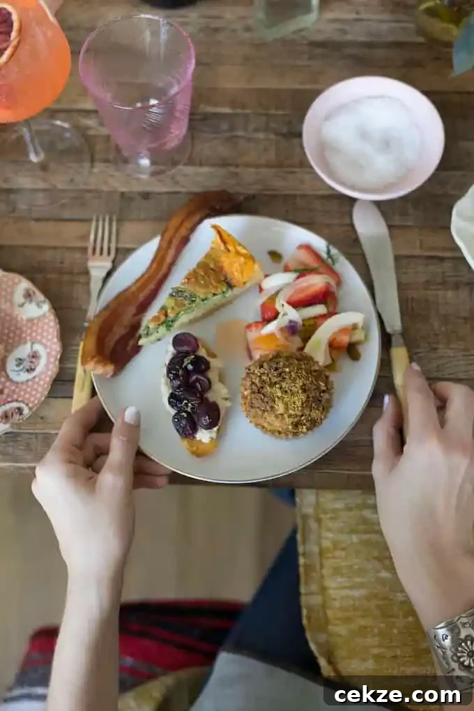 A white plate filled with food sitting on a wood table with a woman's hand holding a knife on one side and there's a fork on the other. 