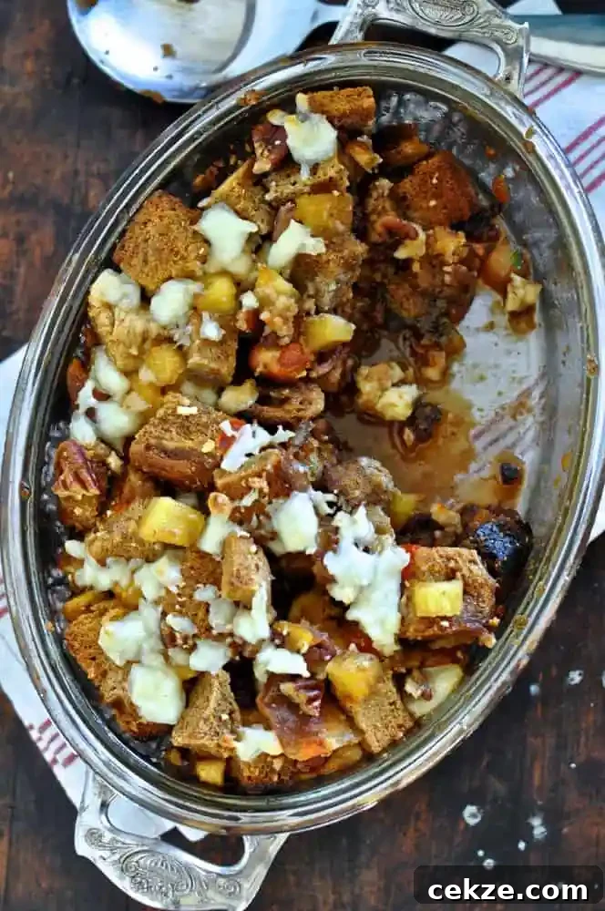 A baking dish filled with capirotada made with pineapple and queso fresco and bread sitting on a wood table. 