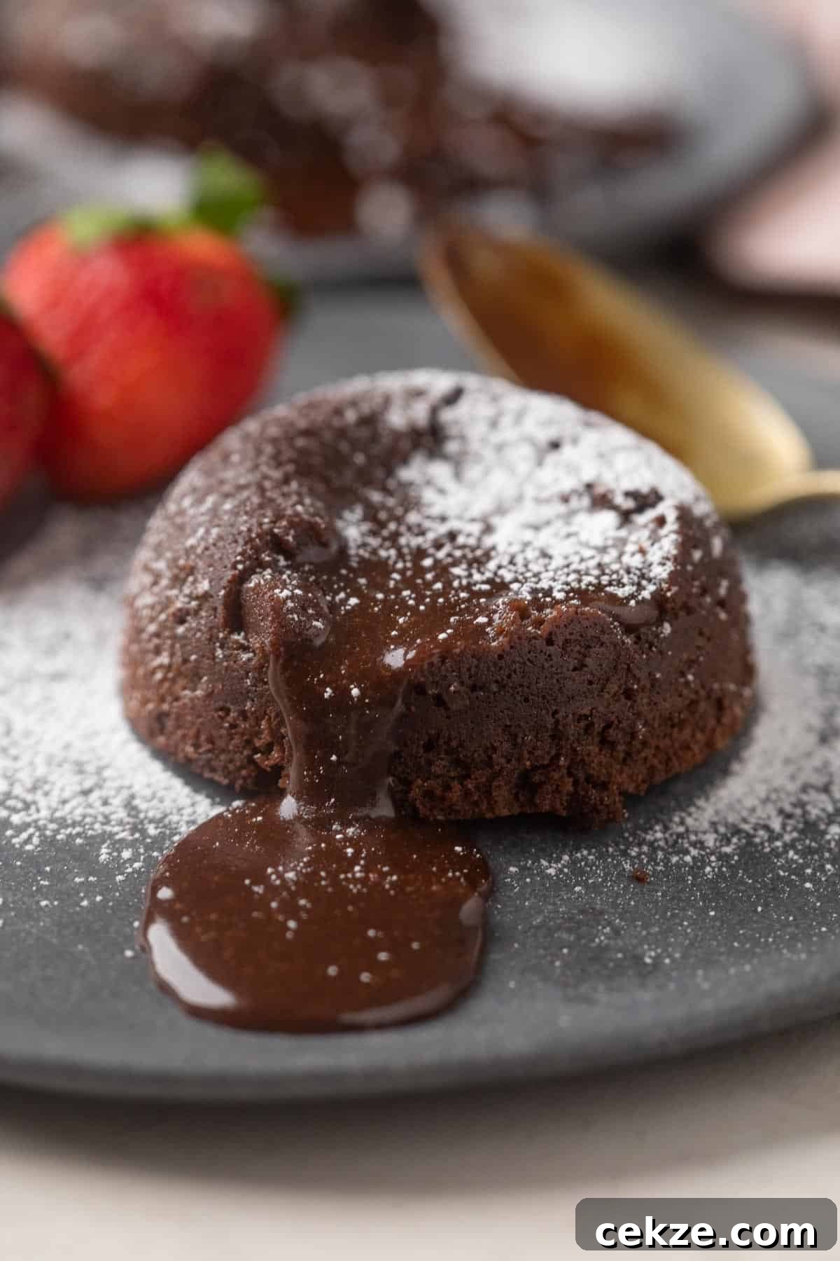 Picture of chocolate oozing out of mocha lava cake with strawberries on the side