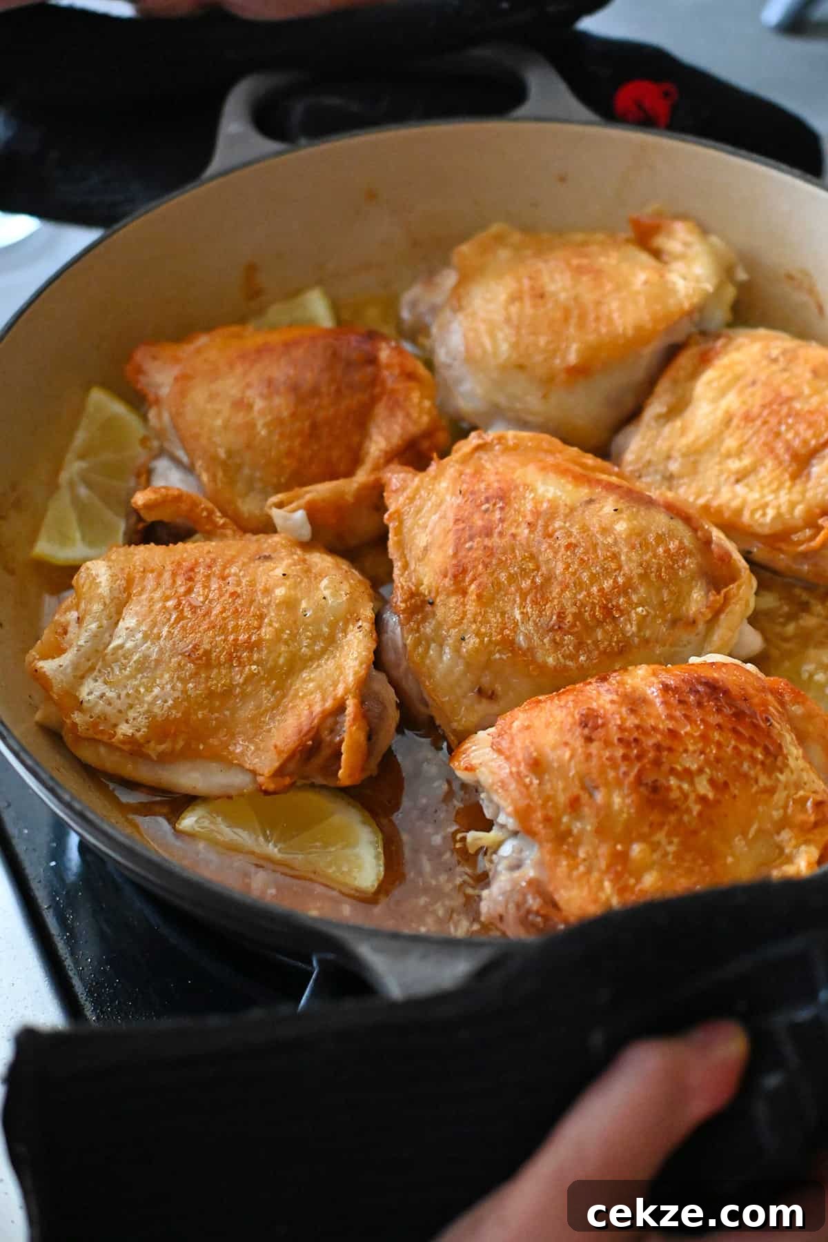 An overhead shot of a skillet filled with lemon garlic chicken thighs before it is put in a hot oven.