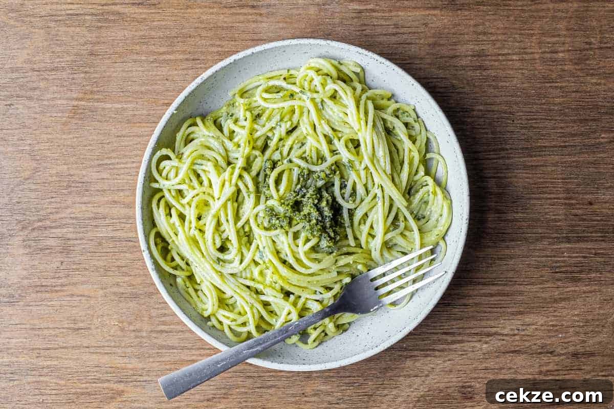 Creamy Pistachio Pesto Pasta Recipe for Quick Weeknight Meals 2 A fork wraps around spaghetti with Pistachio Pesto in a large bowl
