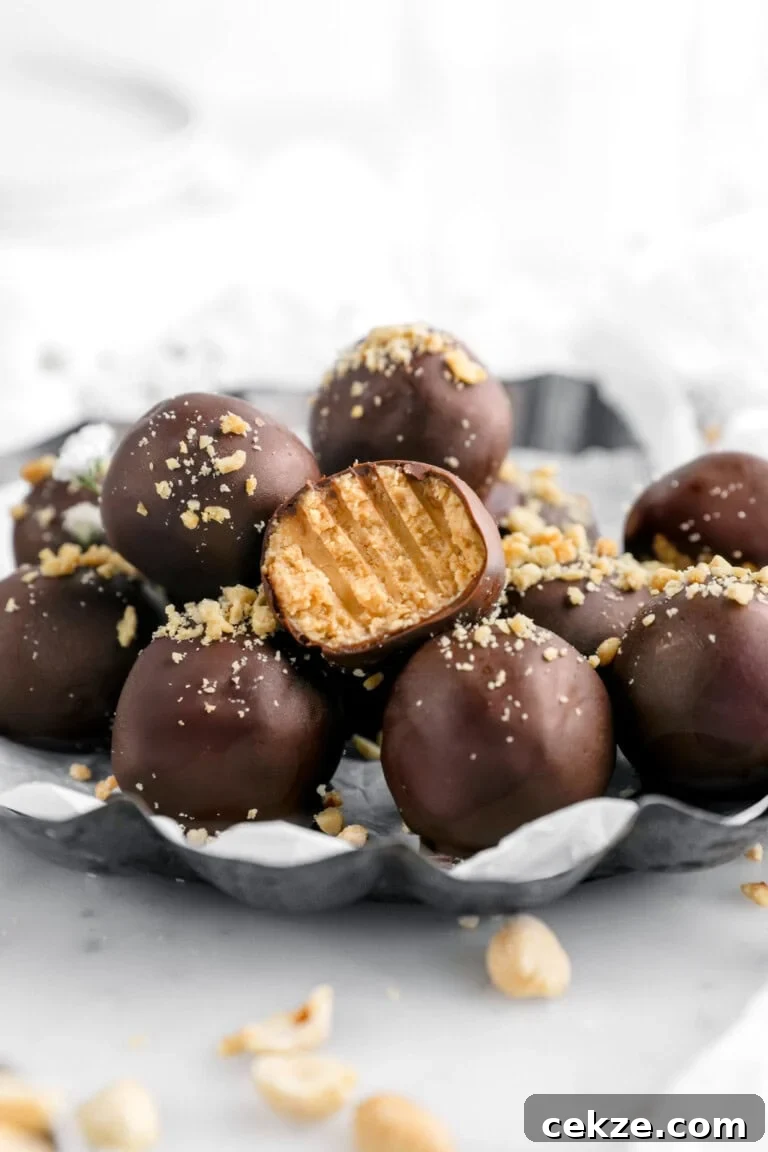 close up of peanut butter balls on parchment lined scalloped plate with one truffle missing a bite.