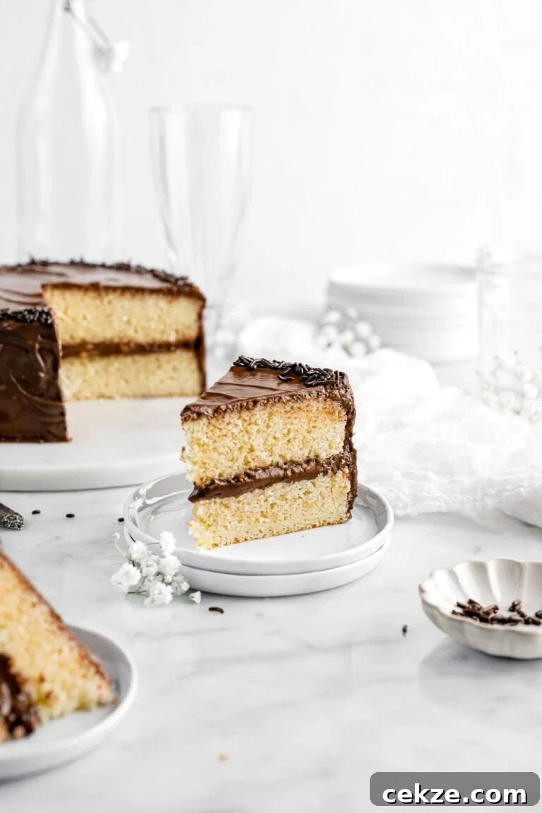 slice of cake on two stacked plates with cake behind and flowers around.