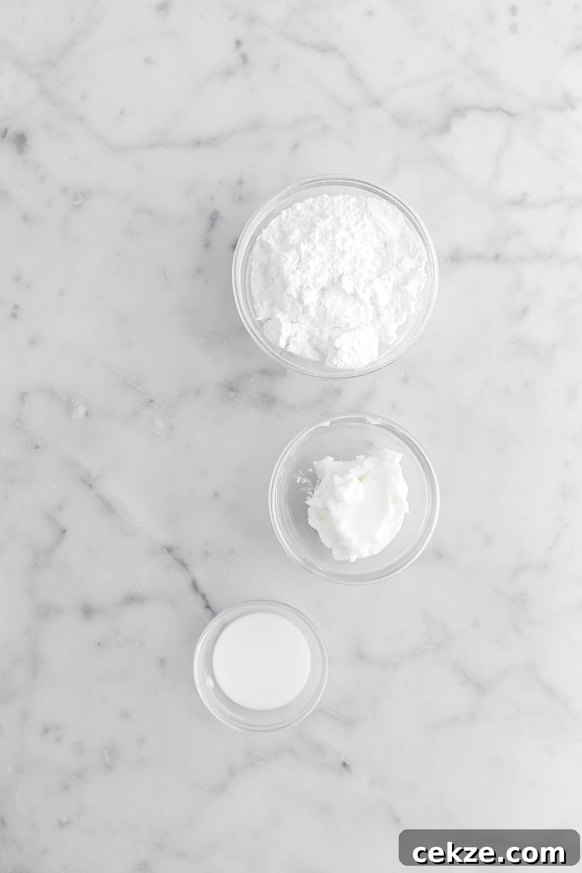 powdered sugar, shortening, and milk on marble surface.