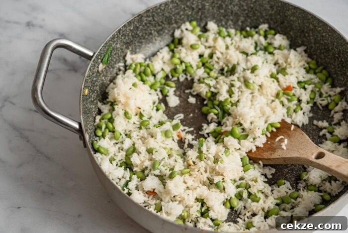 Rice and edamame cooking in a skillet.