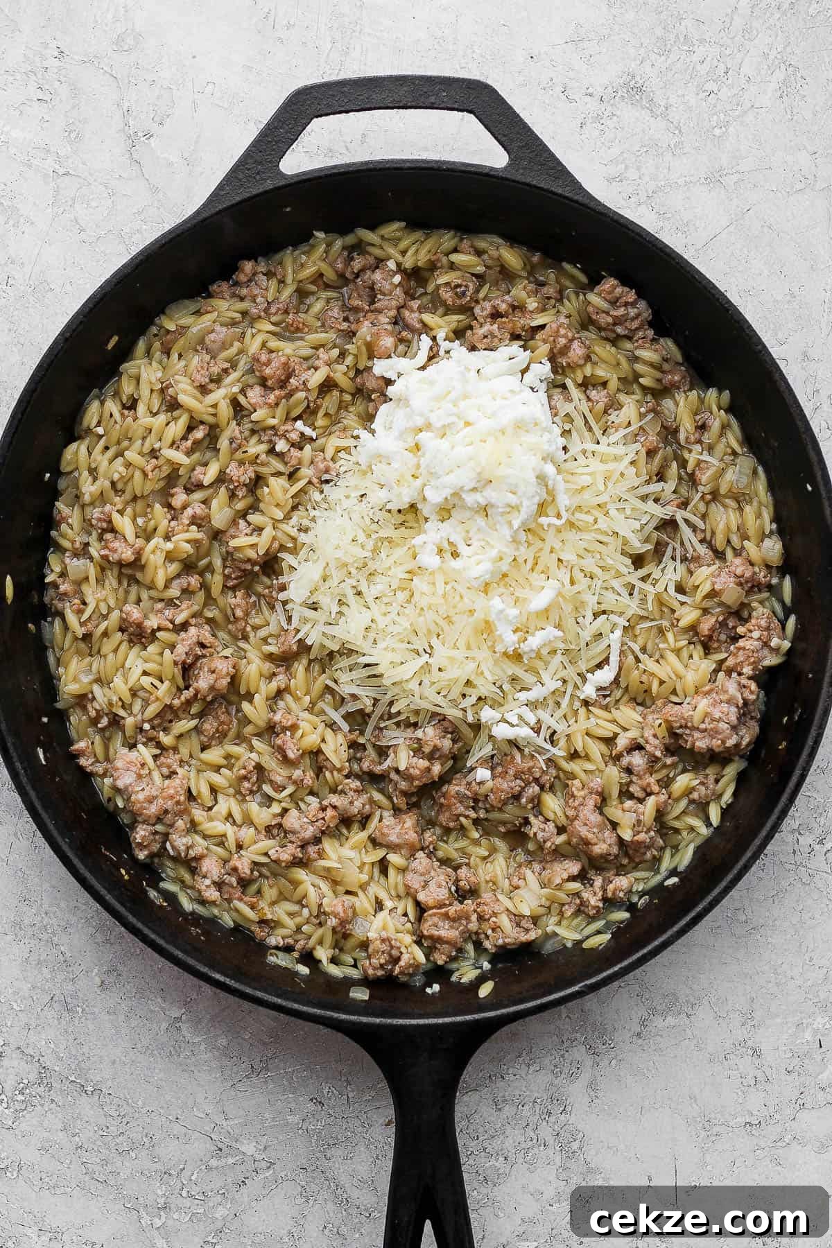The sausage skillet with the orzo fully cooked and cheese added on top.