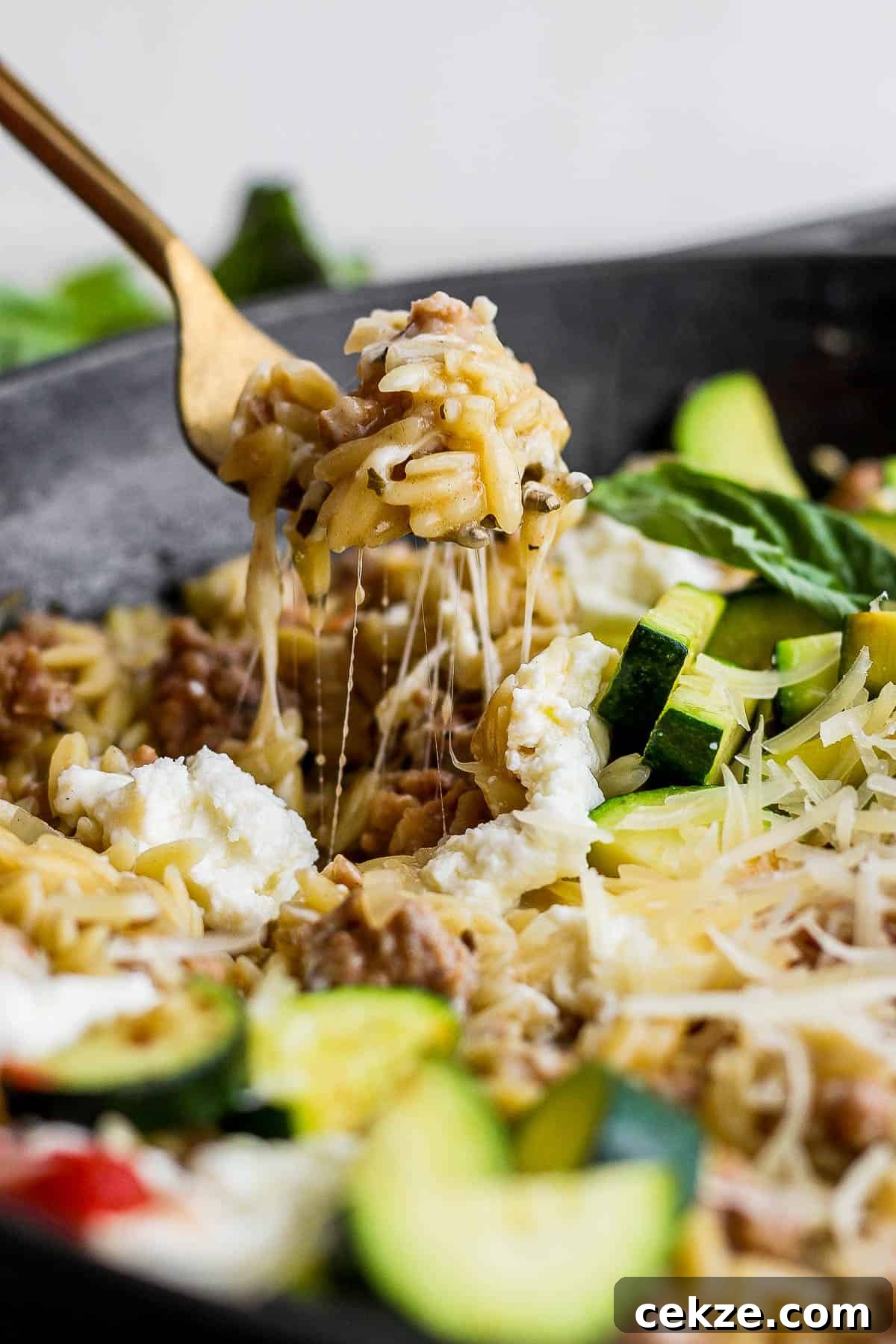 A fork scooping some of the sausage zucchini skillet out of the skillet.