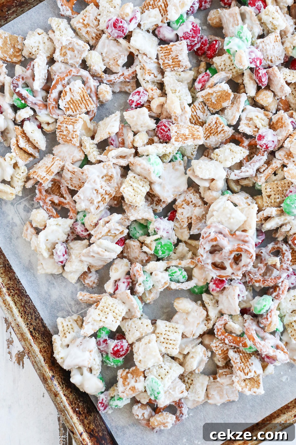 pretzels, Chex cereal, peanuts and m&m's coated in a heavy amount of melted white chocolate on a parchment lined baking sheet. 