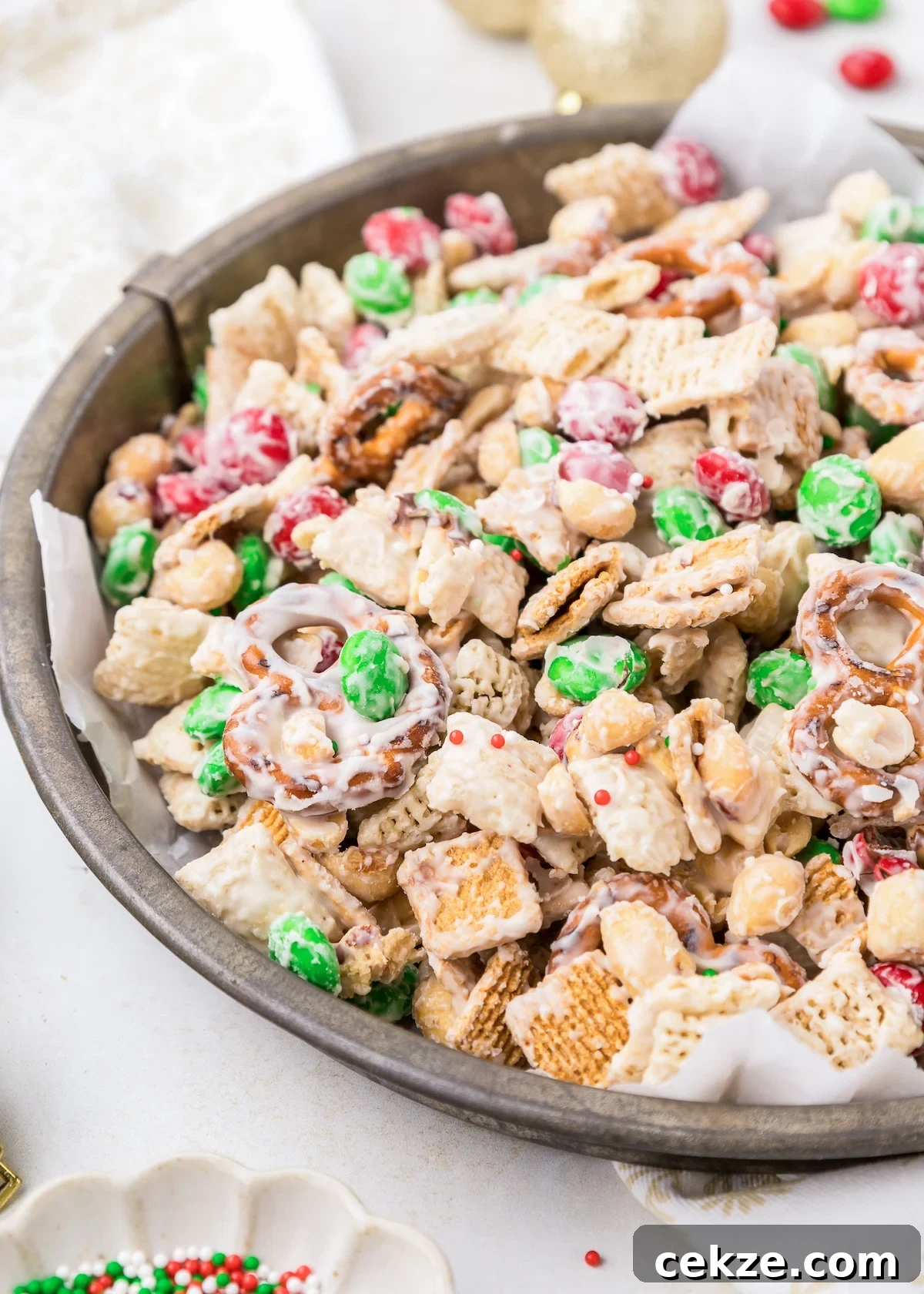 a decorative container full of christmas white trash mix with green m&m's and red sprinkles. 
