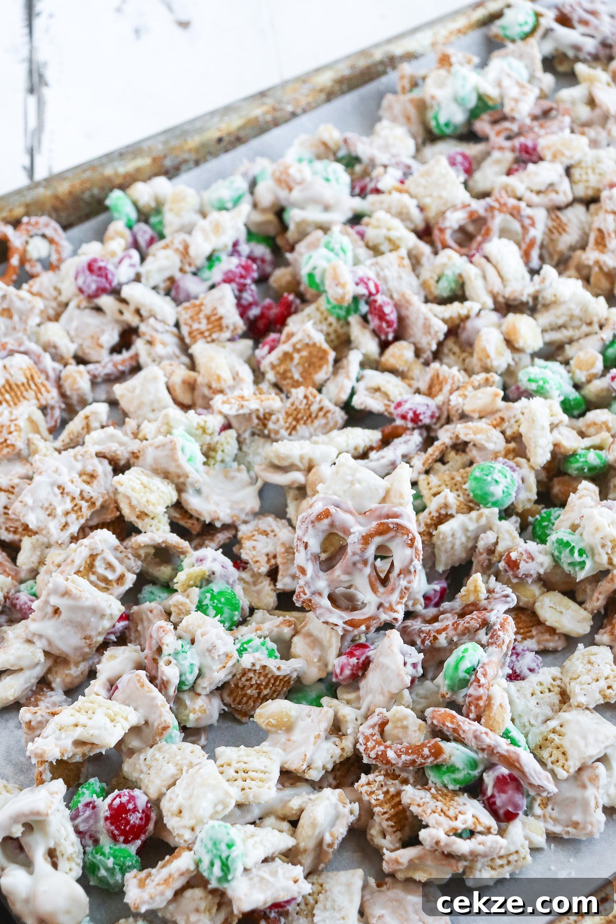 prepared white trash candy snack mix on a large baking sheet lined with parchment paper.