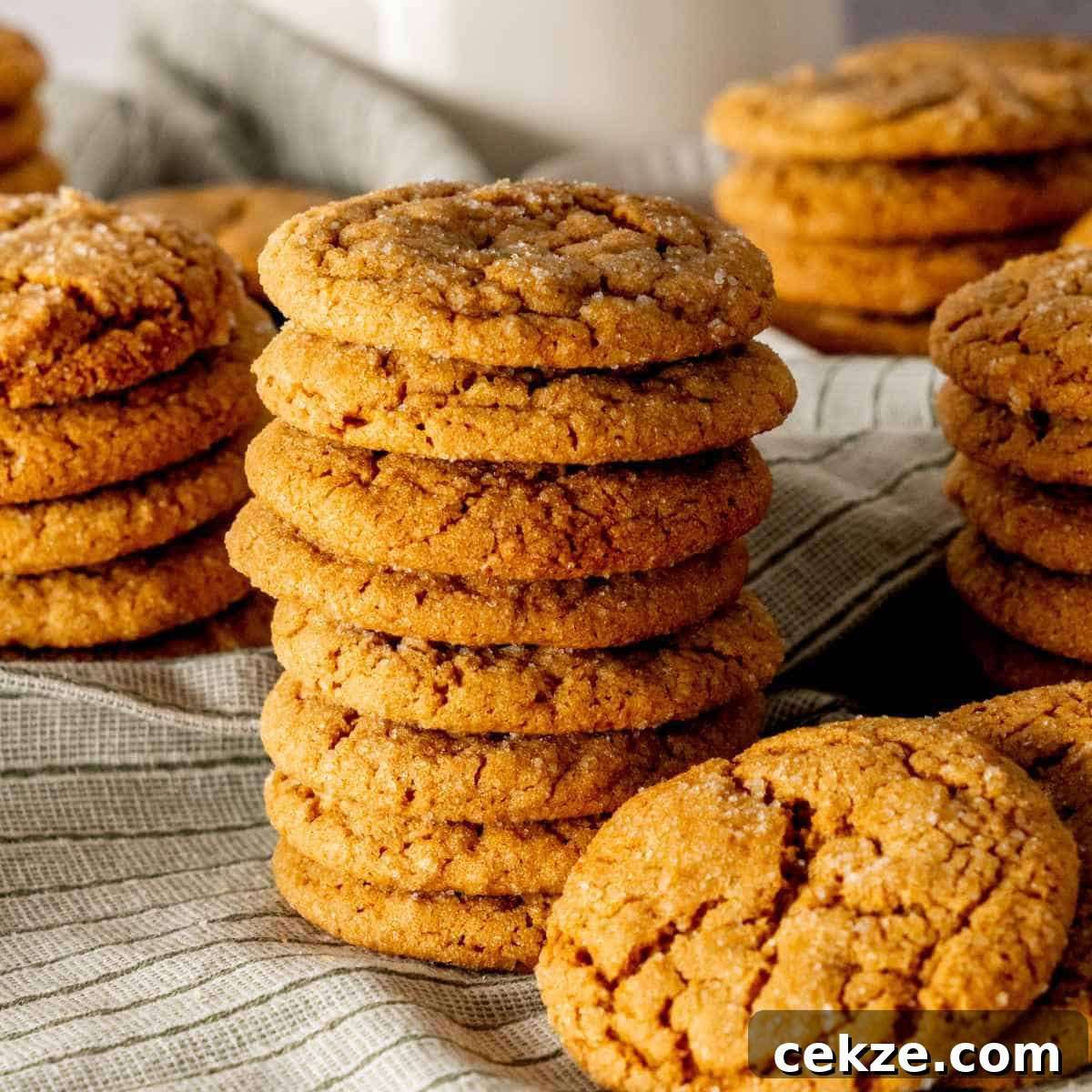 Molasses cookies in stacks with a white mug in the background.