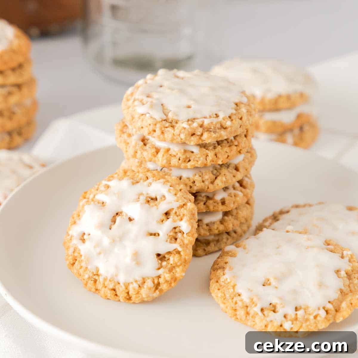 Old Fashioned Iced Oatmeal Cookies stacked and scattered on white plate.