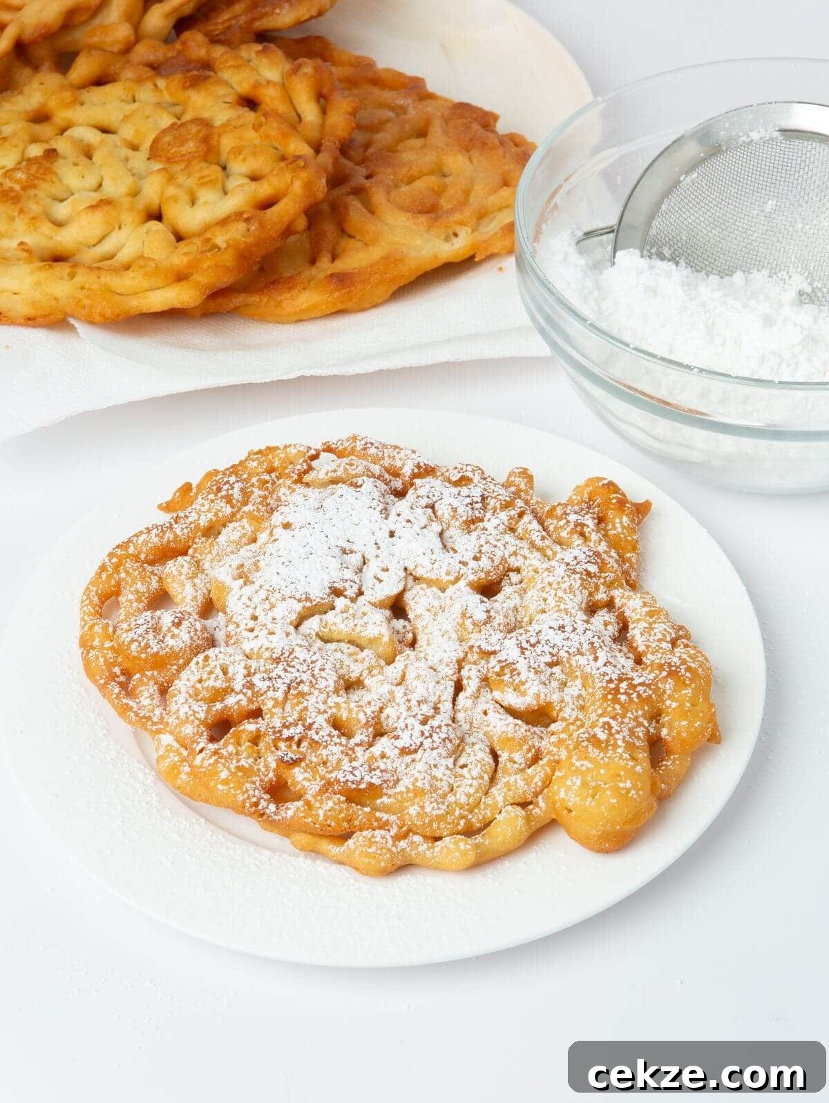 funnel cake on white plate with powdered sugar