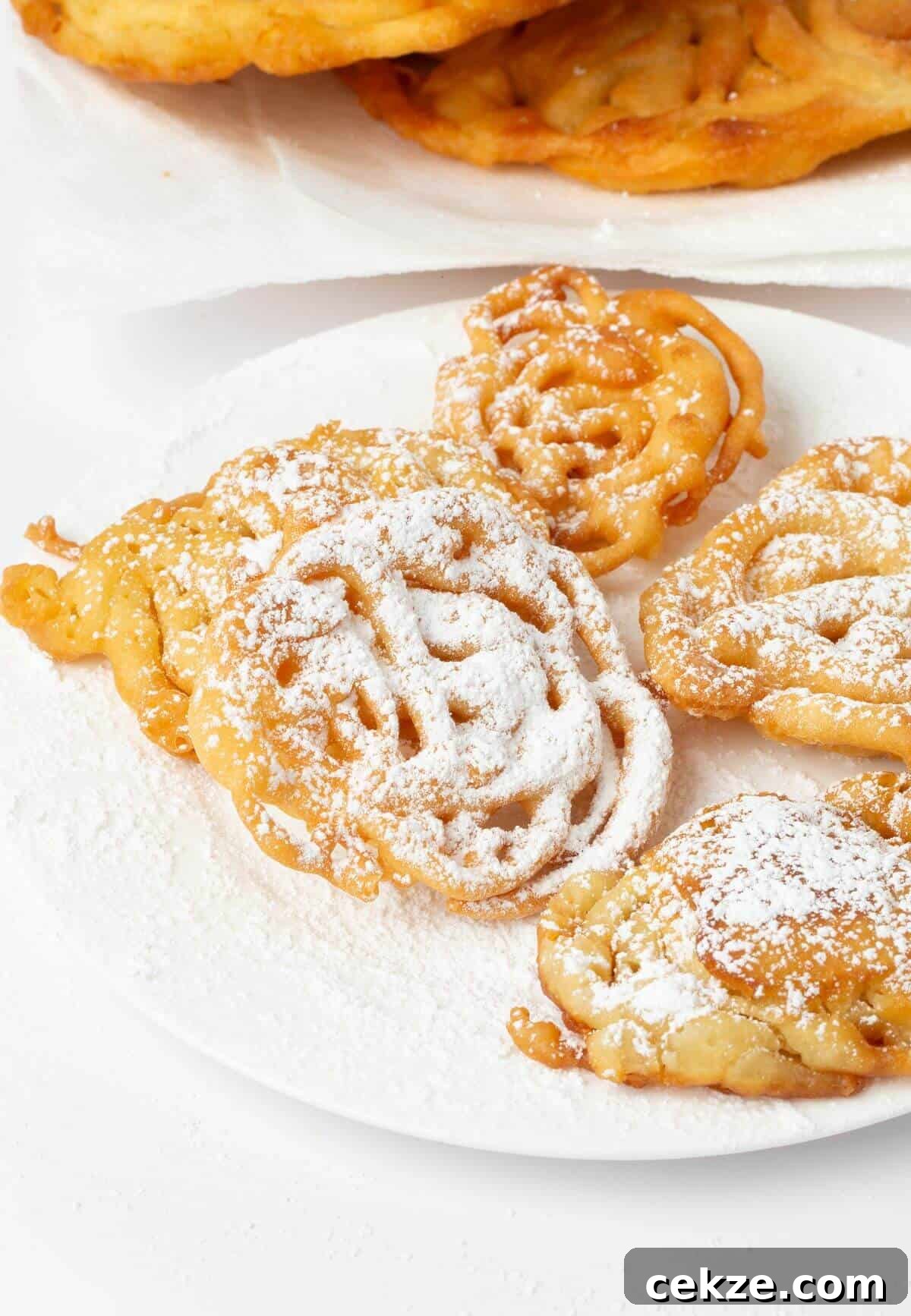 easy funnel cakes on white plate with powdered sugar