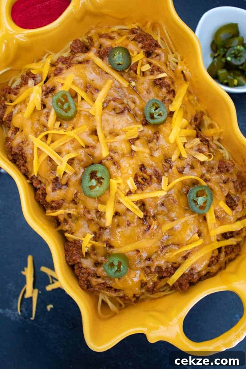 Chili Spaghetti Casserole topped with jalapeno slices in a yellow scalloped bowl.