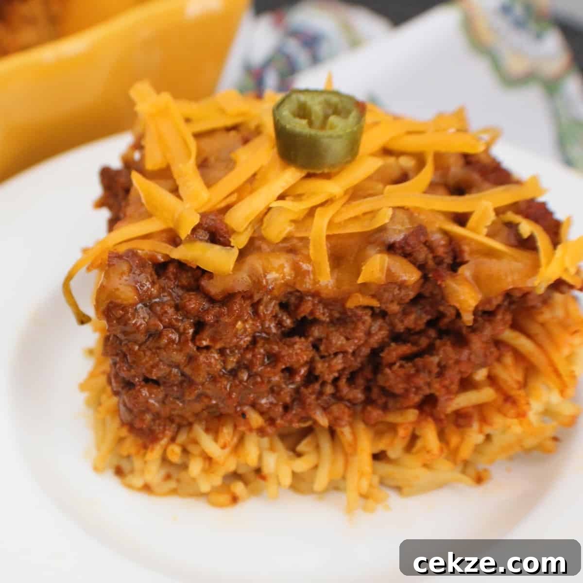 Chili spaghetti pie on white plate garnished with a slice of jalapeno.