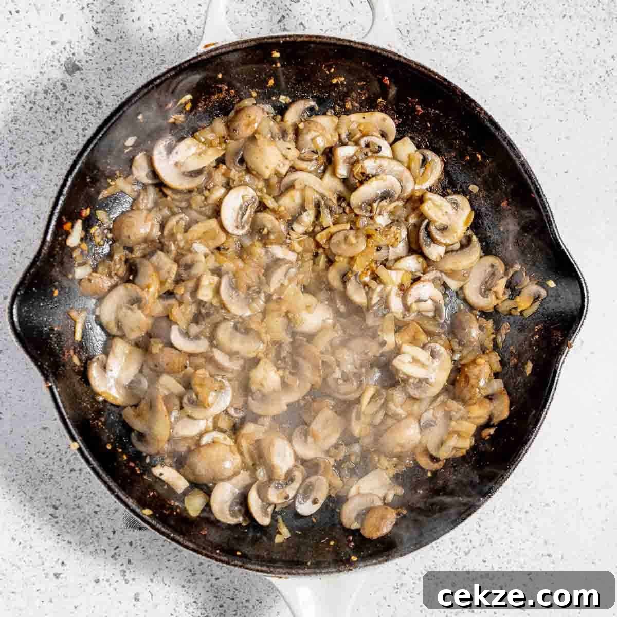 Overhead view of process shot 2 - adding mushrooms, garlic, and onion to the skillet and sautéing.