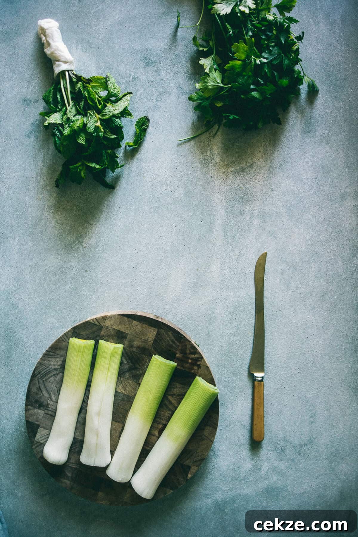 Leek and Cheese Pie Recipe: Flaky Savory Tart with Gruyère 3 leeks and herbs on a chopping board