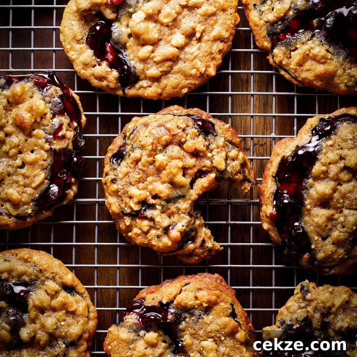 Blueberry pie cookies resting on a wire baking rack. One of the cookies has a bite taken out of it.