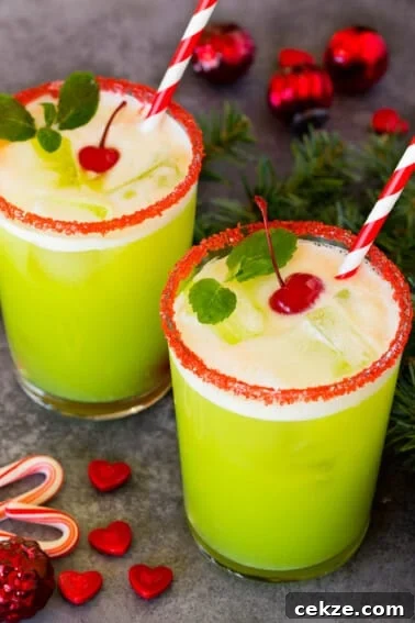 Festive Christmas Jello Shot Recipes for Holiday Parties 11 Cups of Grinch punch topped with cherries and mint sprigs.