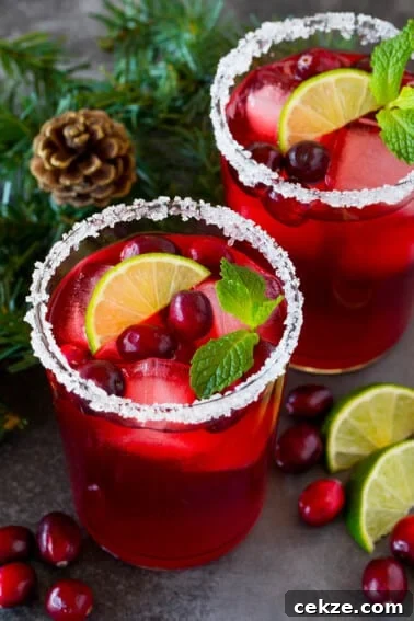 Festive Christmas Jello Shot Recipes for Holiday Parties 8 A cranberry margarita in a sugar rimmed glass with garnishes of fresh berries, lime and mint.
