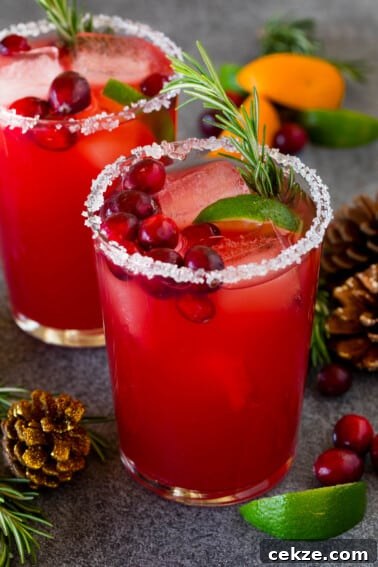 Festive Christmas Jello Shot Recipes for Holiday Parties 10 A Christmas margarita with a sugar rim on the class, and garnishes of cranberry, lime and rosemary.