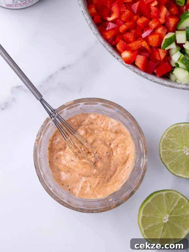 small glass bowl with whisked together creamy dressing, small whisk in the mixture