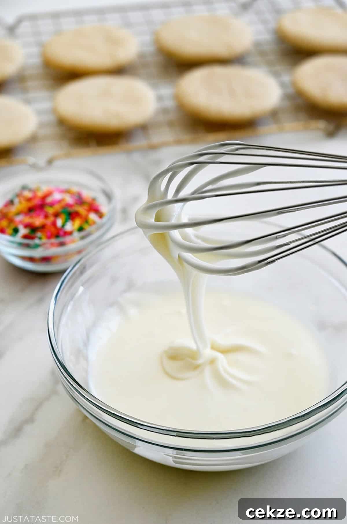 Perfect Sugar Cookie Icing Recipe for Smooth, Glossy Frosting 3 A whisk over a bowl containing frosting made from confectioners' sugar, butter and whole milk.