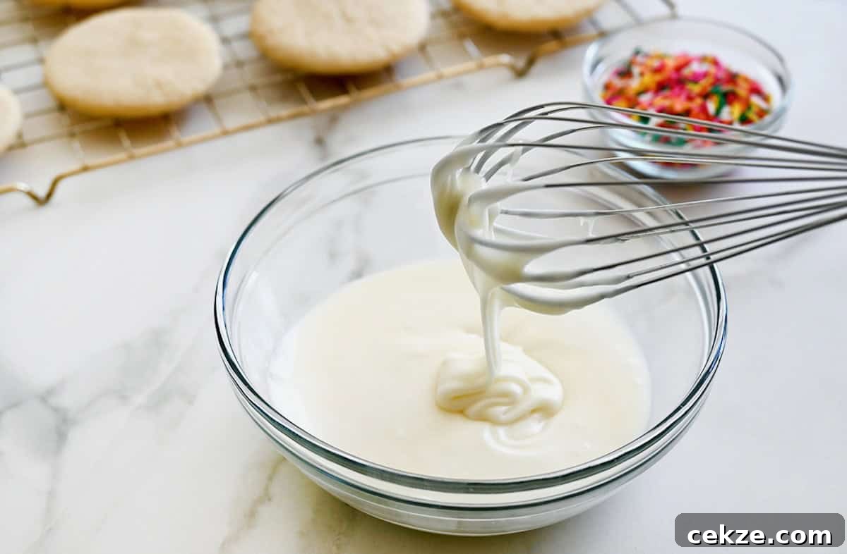 Perfect Sugar Cookie Icing Recipe for Smooth, Glossy Frosting 5 A whisk over a clear bowl containing easy icing made with butter.
