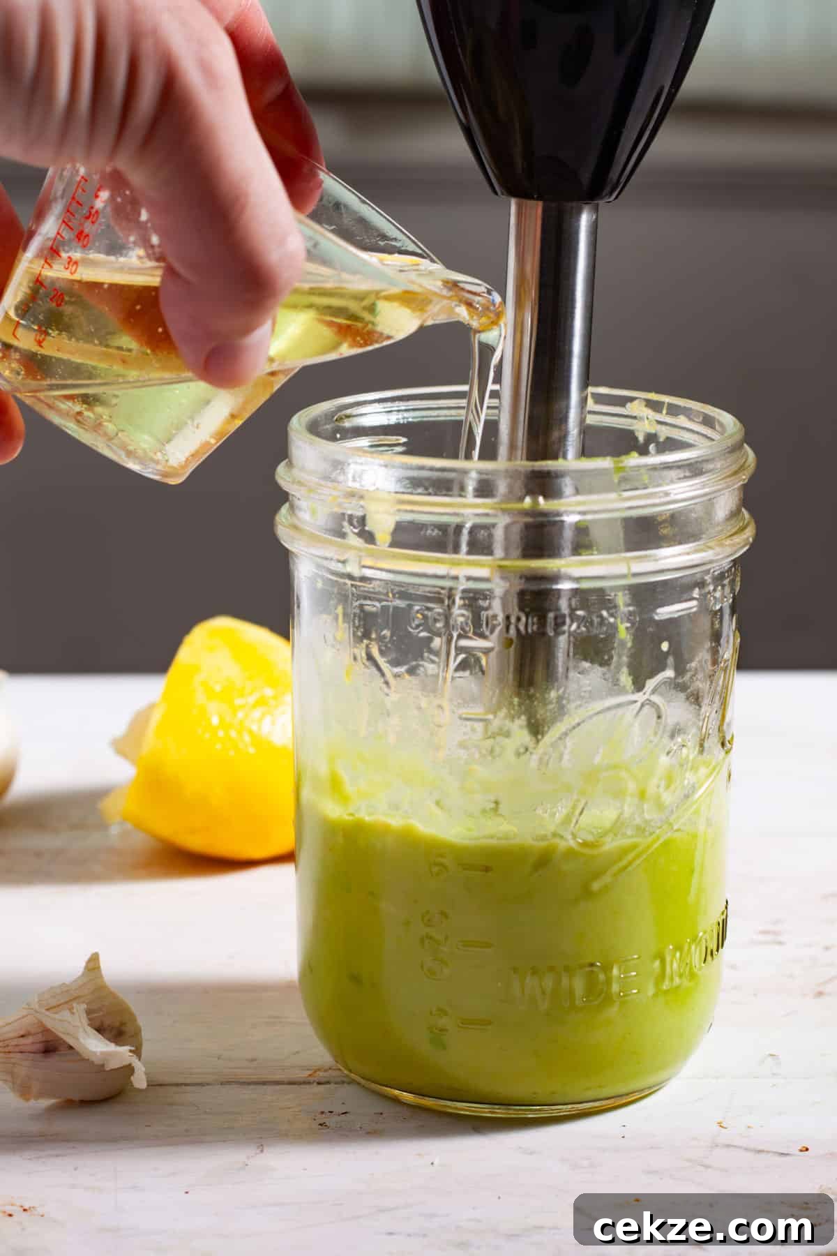 Oil getting poured into a mason jar to make avocado aioli.
