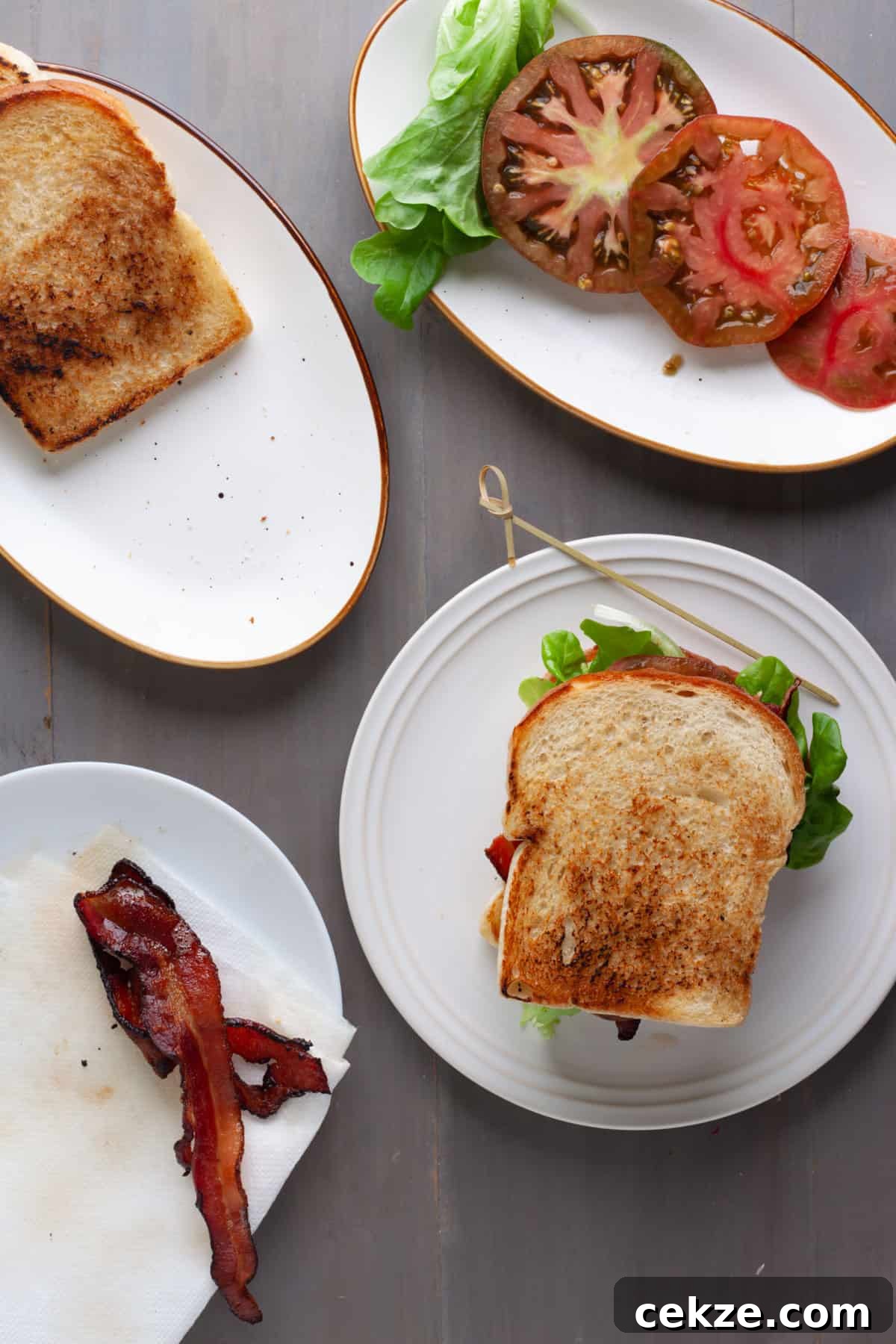 An avocado BLT on a white plate with a toothpick on the side.