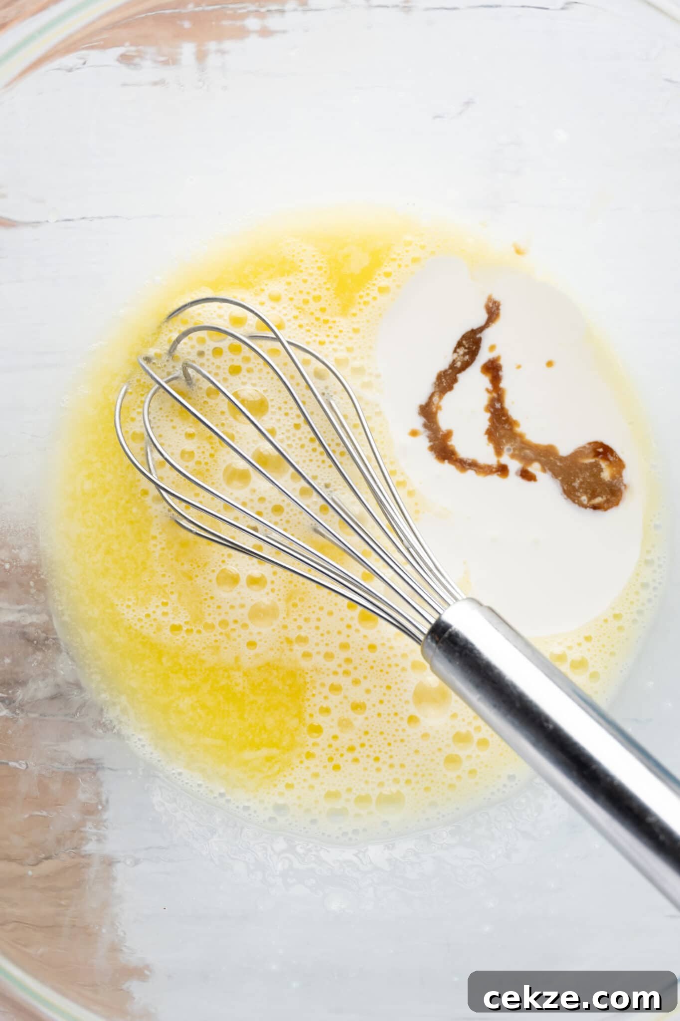 A bowl of wet ingredients against a rustic table top. 