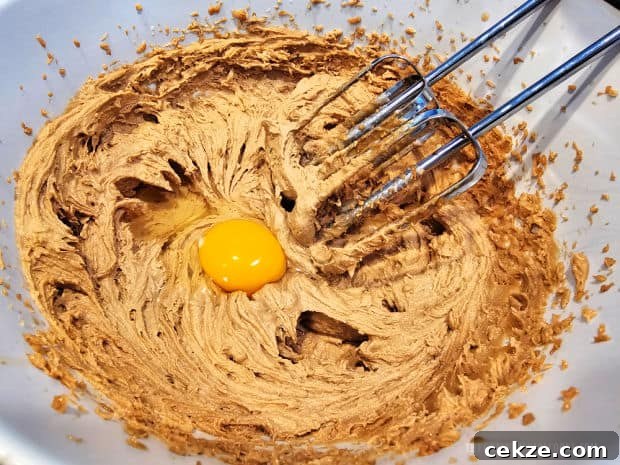 After mixing dough, an egg is beaten into the mixture in the bowl.