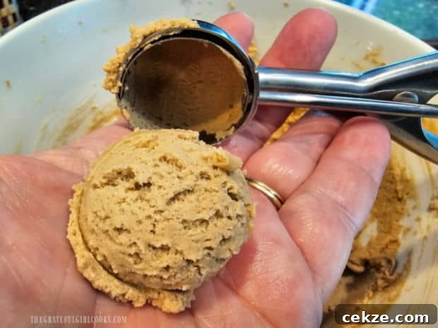 Cookie dough is scooped out and rolled into a ball.