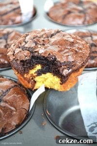 Vertical photo of Deep Dish Brookies with a bite out of one on top of a muffin pan. 
